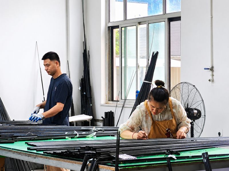 Workers inspecting and organizing finished fishing rod blanks Workers inspecting and organizing finished fishing rod blanks